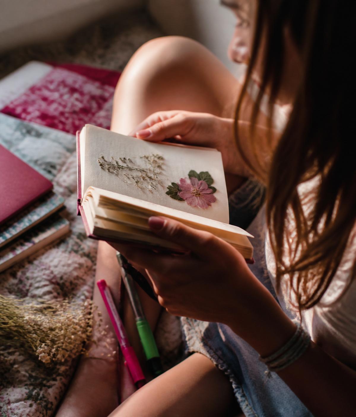 Teenage girl's hands holding a journal with a pressed flower
